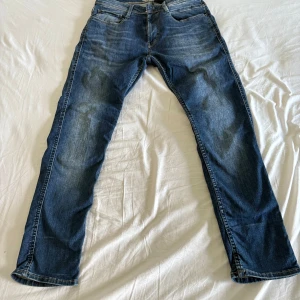 Blå jeans Grant 521 straight fit - Snygga blå jeans från Grant, modell 521, med klassisk slim fit och fem fickor. Jeansen har en mörkblå tvätt med slitningar och kontrastsömmar. Perfekt för dig som gillar en enkel och tidlös look. Materialet är robust denim i bomull.