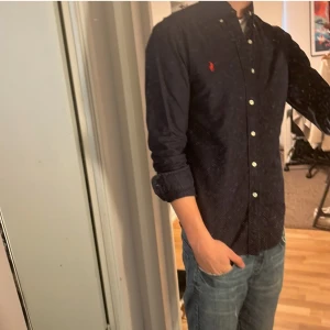 Ralph Lauren skjorta - Tja säljer en Ralph lauren skjorta i färgen marinblå och i storlek S. Nypris 1595 KR mitt pris 299 KR. Inga defekter som hål eller fläckar. Skriv vid frågor eller funderingar.