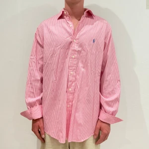 Rosa randig Ralph Lauren Skjorta - Vit/ rosa randig Ralph lauren skjorta || Storlek L (Custom Fit) || Skjortan är i bra skick || Mitt pris 599kr || Modellen på bilden är 170cm och väger 62kg || Tveka inte på att höra av dig vid frågor eller funderingar 