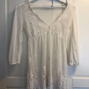 Vit babydoll topp i spets  - Supersöt vit babydoll topp från Zara Collection i mesh och broderade blommor🌸. V-ringad med spetskant, tre små knappar framtill och trekvartsärmar💗💗 Perfekt för sommarens alla tillfällen, ger en romantisk och bohemisk vibe. Liten reva i ena ärmen se sista bilden😊