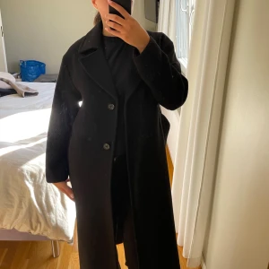 Svart lång kappa med bälte  - Säljer min svarta lång kappa från Kappahl i storlek xs, har endast använt ett par få gånger 