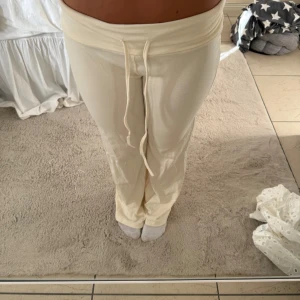 Krämvita mjukisbyxor med snörning - Säljer ett par krämvita mjukisbyxor med bred midja och snörning framtill. Byxorna har en loose passform och är tillverkade i mjukt bomullsmaterial. Perfekta för chill dagar och har en enkel, stilren look som är lätt att matcha.