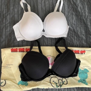 Behå 2 stycken  - Två snygga behå, en i svart och en i vit, båda med diskret randigt mönster och spetsdetaljer längs kanterna. Axelbanden är justerbara och kuporna är formade för extra stöd. Använd max 3 gånger 