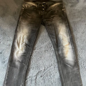 dondup george - Säljer ett par mörkgrå Dondup George med riktigt snygga slitningar, dock en defekt mellan benen, se på bild 3! Det syns ej vid användning så länge man inte stretchar. De är storlek w29 men skulle säga att det passar bättre som w28 och passar upp mot längd på 175! Jag kan skicka mer bilder på etiketter och deffekter till seriösa köpare! Mvh 