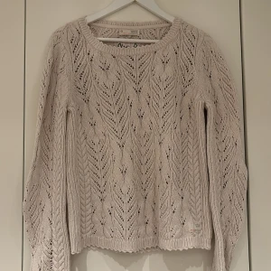 Beige stickad tröja från Odd Molly - Supersnygg beige stickad tröja från Odd Molly med hålmönster och rund hals. Tröjan har långa ärmar och fina detaljer, inklusive broderad logga på ryggen. Perfekt för lager-på-lager och en mysig stil.