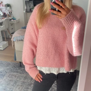 Rosa stickad tröja - Mysig rosa stickad tröja med oversized passform och långa ärmar. Tröjan har en enkel design med breda muddar vid ärmslut och nederkant. Perfekt att styla med jeans för en avslappnad look.