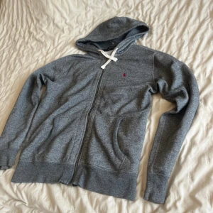 Polo Ralph Lauren Hoodie - Säljer en grå hoodie från Polo Ralph Lauren med vit snörning och röd logga. Storlek medium och bra skick.