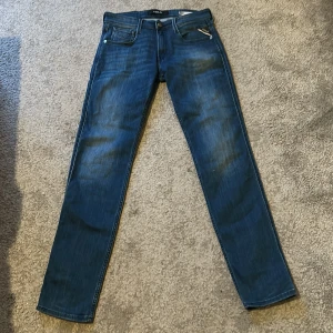 Blå slim fit jeans från Replay Anbass - Säljer ett par blå jeans från Replay, modell Anbass. Jeansen har en snygg wash och raka ben med smal passform. Perfekta för dig som gillar stilrena och bekväma jeans. Storlek 32 i längd och 28 i waist