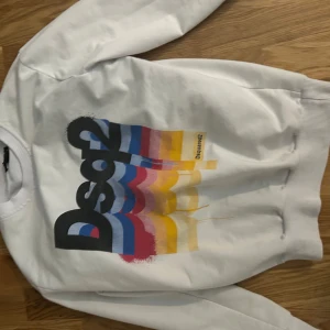 Dsquared2  - Liten i storlek Vit sweatshirt från Dsquared2 med stort grafiskt tryck i svart, blått, rött, rosa och gult på framsidan. Tröjan har rund halsringning och ribbade muddar vid ärmslut och nederkant. Perfekt för en färgstark och trendig look.