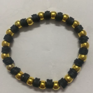 Guld- och svart pärlarmband - Snyggt armband med glänsande guldfärgade pärlor och svarta detaljer. Perfekt för att ge en stilren touch till din outfit. Elastiskt band för enkel passform.