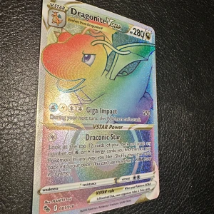 Dragonite VSTAR Pokémonkort - Säljer ett Dragonite VSTAR Pokémonkort med holografisk yta. Kortet har 280 HP och attacker som Giga Impact och Draconic Star. Kortet är på engelska och har färger som gult, grönt och blått. Perfekt för samlare eller Pokémon TCG-spelare.