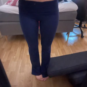 Mörkblå bootcut byxor från bubbelroom - Säljer ett par mörkblå bootcut byxor från Double Up i storlek S. Byxorna har en hög midja och är tillverkade av ett stretchigt material som består av 80% återvunnen viskos. Perfekta för en trendig och bekväm look.