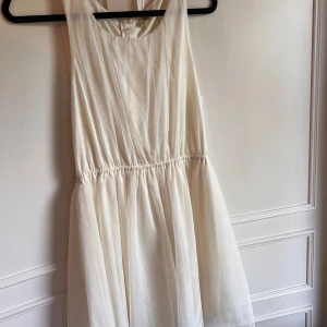 Festklänning, tyll, NWT - Säljer en vit klänning från H&M. Klänningen har en dragkedja i ryggen och är tillverkad i 100% polyester. Perfekt för sommarens alla festliga tillfällen. 🕊️