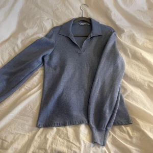 Ljusblå stickad tröja med krage från Dobber - Säljer en ljusblå stickad tröja från Dobber i storlek S. Tröjan har lång ärm, klassisk krage och v-ringning. Perfekt för dig som gillar en enkel men stilren look. Materialet känns mjukt och bekvämt mot huden.