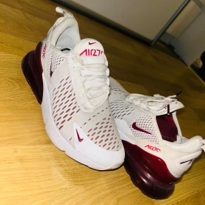 Nike Air Max 270 vita och vinröda sneakers - Nike Air Max 270 sneakers i vitt med vinröda detaljer. Skorna är använda 3 gånger. 