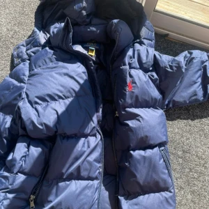 Blå pufferjacka från Polo Ralph Lauren - Säljer en snygg blå pufferjacka från Polo Ralph Lauren med röd broderad logga på bröstet. Pris kan diskuteras 💞