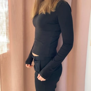 Svart långärmad topp - Snygg svart långärmad topp med en tight passform. Perfekt för en stilren look. Toppen har en two topp passform. S/Xs Toppen har en enkel design som gör den lätt att matcha med olika outfits. 