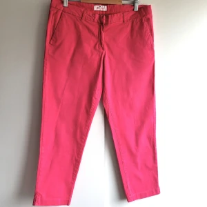 Rosa chinos från Blue Motion, stl 42 - Snygga rosa chinos från Blue Motion i storlek 42. Byxorna har klassisk passform med raka ben, sidfickor fram och knäppning bak. Tillverkade i mjuk bomull som känns skön mot huden. Perfekta för dig som vill sticka ut med färg. Perfekt skick.