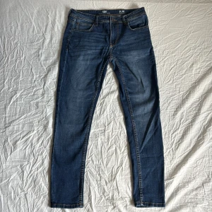 Mörkblå skinny jeans från FSBN - Snygga mörkblå skinny jeans från FSBN med klassisk femficksdesign och gul kontrastsöm. Jeansen är tillverkade i en stretchig bomullsblandning för extra komfort och har en smal passform som sitter tajt längs benen.