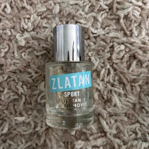 Zlatan Sport parfym - Fräsch parfym från Zlatan Ibrahimović med sportig känsla. Flaskan är genomskinlig med ett stilrent blått och vitt tryck samt en silvrig metallkork. Perfekt för dig som gillar energiska och fräscha dofter. Mer än halvfull