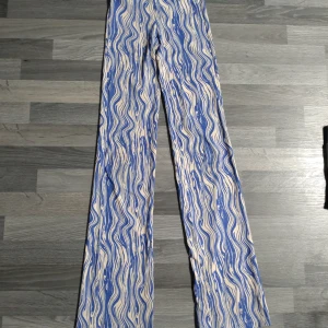 Mönstrade leggings / tights från Monki XXS - Säljer ett par unika byxor från Monki i storlek XXS med blåvitt/beiget vågigt mönster. Lite bootcut, tillverkade i ett stretchigt, mjukt material som sitter skönt. Perfekta för dig som gillar att sticka ut med coola mönster och färger.