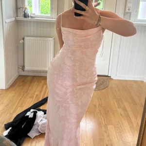 Ljusrosa långklänning från Gina Tricot - Supersöt långklänning i ljusrosa från Gina Tricot med blommigt mönster. Klänningen har tunna axelband, cowl neck och en figurnära passform. Aldrig använt den, storlek 38 men passar en 36 och 40 också. 💖💖