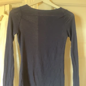 Mörkblå intimissimitröja - En enkel och stilren mörkblå intimissimitröja med rund halsringning. Tröjan är tunn och har en smal passform, perfekt att bära som lager eller för en minimalistisk look. Materialet känns mjukt mot huden.