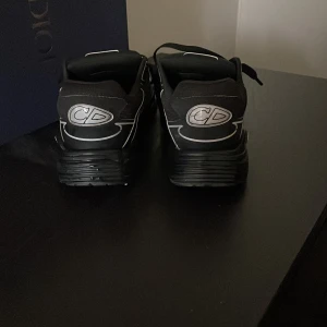 Svarta Dior B30 sneakers strl 44 - Vid frågar bara att skriva Pris kan även diskuteras Säljer ett par svarta Dior B30 sneakers i storlek 44. Skorna har coola vita detaljer, CD-logga bak och snörning framtill. Tillverkade i microfiber och mesh för en modern vibe. Kommer med originalpåse, och box även kvitto. Har bytt sko snören till ett par andra men dem vanliga ingår också även dem som är på just nu 
