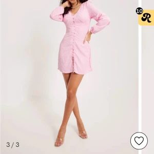 Rosa kortklänning - Supersöt rosa kortklänning med vitt leopardmönster från Nelly . Klänningen har v-ringning, långa ärmar och knappar framtill. Figurnära passform och lätt, skönt material som passar perfekt till varmare dagar.