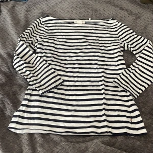 Randig långärmad tröja Holly & Whyte - Snygg långärmad tröja från Holly & Whyte by Lindex i klassiskt marinblått och vitt randigt mönster. Tröjan har en rak passform och är tillverkad i mjuk bomull, perfekt för en avslappnad och stilren look. Inprincip helt ny, använd få gånger❤️