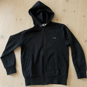 Comme des Garçons Play hoodie - Cdg zip hoodie i storlek M, originalpris är 2599kr på NK men köptes på här på plick och fick inte med något kvitto. Hoodien är använd men fortfarande i bra skick!