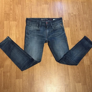 Replay jeans blå straight - Snygga blå jeans från Replay med klassisk femficksdesign. Jeansen har raka ben, normal passform och Märkesdetalj på myntfickan och röda sömmar vid knappen. Perfekta för dig som gillar stilrena och bekväma jeans. 