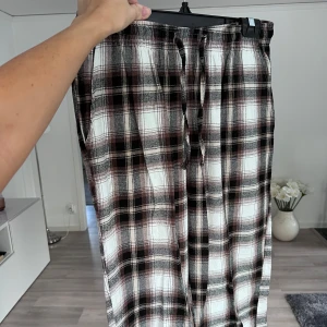 Rutiga mjukisbyxor med snörning - Supermysiga mjukisbyxor i rutig design med svart, vit och brun färg. Byxorna har snörning i midjan. Perfekta att sova i eller bara under en chill dag hemma. Önskar du veta exakta mått? Tveka inte att höra av dig! 🖤🤎🤍