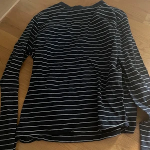 Svartvit randig långärmad tröja L - Svart långärmad tröja med tunna vita horisontella ränder. Klassisk och enkel design med rund halsringning. Perfekt för dig som gillar en stilren och avslappnad look. Mjuk och skön känsla, passar till jeans eller kjol.