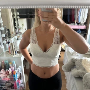 Vit spetsig croppad topp från NLY One - Superfin vit croppad topp från NLY One i spets med v-ringning och breda axelband. Toppen har dragkedja i ryggen och är fodrad under spetsen. Perfekt för dig som gillar romantisk och feminin stil!