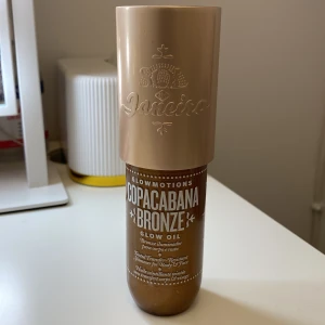 Sol de Janeiro Copacabana Bronze Glow Oil - Glow Oil i nyansen Copacabana Bronze från Sol de Janeiro. Ger en skimrande, solkysst bronzig look med massor av glow. Oljan är brun med guldskimmer och passar perfekt för att highlighta kropp och ansikte. Kommer i en snygg beige och brun flaska.