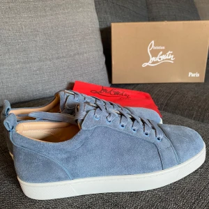 Blå mockasneakers från Christian Louboutin - Säljer ett par snygga blå sneakers med den ikoniska röda sulan – inspirerade av Louboutin. Storlek 43, helt nya och oanvända.  Tillverkade i mjukt läder och mocka, med hög finish och perfekt passform. En exklusiv look som sticker ut utan att vara överdriven.  Levereras med låda, dust bag och extra skosnören.  Hör av dig för fler bilder eller mer info!