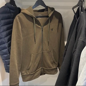 Olivgrön hoodie från Polo Ralph Lauren - Väldigt väl omhändertagen utan några defekter. Originalpris på dessa är nu 2200kr så säljer för mer än 60% billigare!