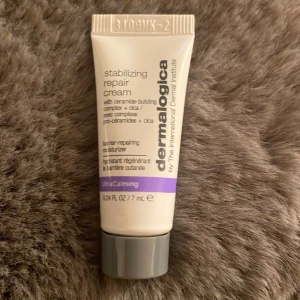 Dermalogica Stabilizing Repair Cream 7 ml - En liten tub med Dermalogica Stabilizing Repair Cream, 7 ml. Krämen är vit med grått lock och har lila detalj. Innehåller ceramider och cica, passar för känslig hud och är en återfuktande ansiktskräm från UltraCalming-serien.