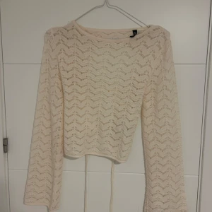 Beige stickad croppad tröja med öppen rygg och knyt - Säljer en beige stickad tröja med lång ärm, croppad modell och snygg öppen rygg med knytband. 