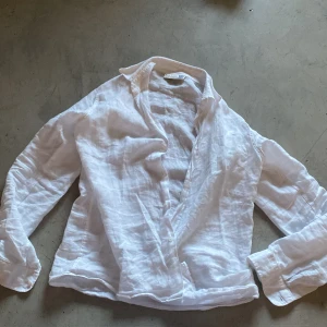 Vit linneskjorta från Dal Lago - Säljer en klassisk vit skjorta i linne från Dal Lago, tillverkad i Italien. Skjortan har lång ärm, krage och knäppning framtill. Perfekt för en stilren och luftig look under varmare dagar.