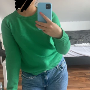 Grön stickad tröja med rund hals - Snygg grön stickad tröja med rund halsringning och långa ärmar. Perfekt att matcha med jeans för en chill och stilren look. Tröjan har ribbade muddar vid ärmslut och nederkant för extra komfort.