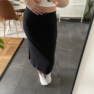 Svart midi kjol - Svart mjuk midi kjol med slit på ena sidan och tajt resår vid höften. Bra skick men lite nopprig då den används några gånger. 💕