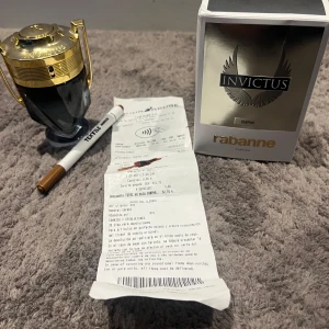 Paco Rabanne Invictus Parfum 100ml - Säljer en lyxig Invictus Parfum från Paco Rabanne, 100ml, ca 70ml kvar i flaskan,Flaskan har en unik troféform i mörkgrått glas med detaljer i glänsande guld. Kommer med originalkartong i silver och guld. En ikonisk doft som sticker ut både i design och känsla.