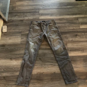 Grå jeans från Jack & Jones - Snygga grå jeans från Jack & Jones med klassisk femficksdesign och raka ben. Jeansen har en stilren look och är tillverkade i mjukt denimtyg. Perfekta för dig som gillar en enkel men trendig stil. Storlek 31 midja och 34 längd 