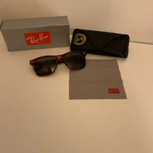 Ray-Ban Wayfarer solglasögon i leopardmönster - Snygga Ray-Ban Wayfarer solglasögon med klassiskt leopardmönster och mörka glas. Bågarna är i plast och har Ray-Ban-loggan på sidan. Kommer med originalfodral och putsduk.