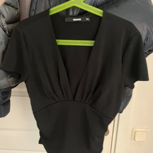Svart v-ringad topp från Bik Bok - Svart topp från Bik Bok med djup v-ringning och korta ärmar. Passar till fest eller middag! Inga defekter❤️ 