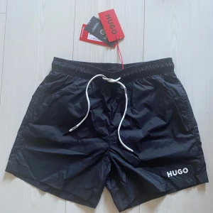 Badbyxor - HUGO - Svarta badshorts från HUGO. Köpte de men var för små för mig. Det är aldrig använda och är i storlek S. Etikett och allt kvar. Hör av er vid frågor!