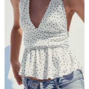 Vit prickig halterneck topp - Säljer denna vita  halterneck topp med svarta prickar och volang nertill. Även figursydd! Helt nya från Zara, alla lappar på! Storlek M. Slutsåld på hemsidan 