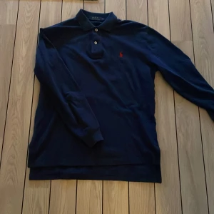 Mörkblå långärmad pikétröja från Polo Ralph Lauren - Säljer en klassisk mörkblå långärmad pikétröja från Polo Ralph Lauren med röd broderad logga på bröstet. Storlek S. Skick 7/10  Perfekt för en stilren och avslappnad look. Pris kan diskuteras vid snabb affär
